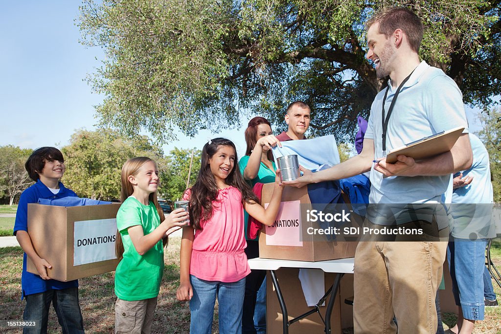 Children and families bringing donations to relief center Children and families bringing donations to relief center.  A Helping Hand Stock Photo