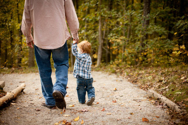 istock Father and Son Holding Hands While Walking through Autumn Woods 155138171