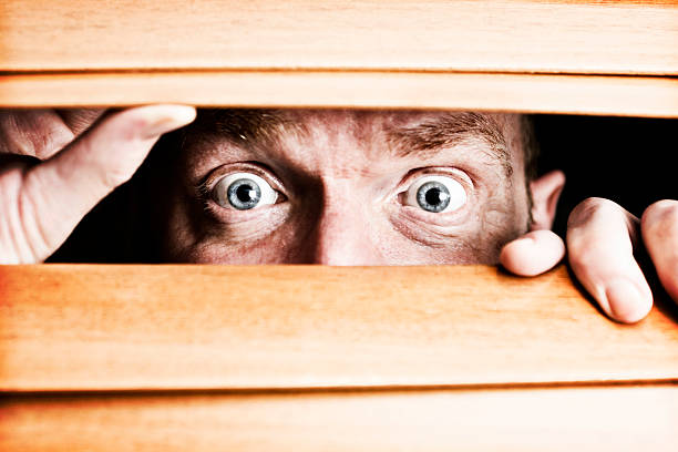 istock Terrified man peeps through wooden blind at something very scary! 155138334