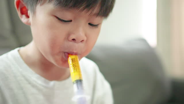 CU Asian little boy taking vitamin liquid supplement.