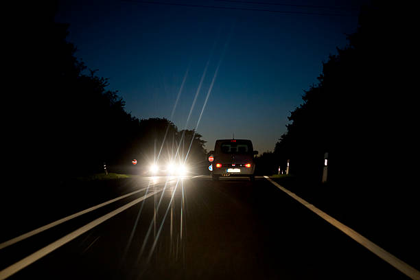 tráfico en countryroad que viene en dirección contraria al atardecer - blinding fotografías e imágenes de stock