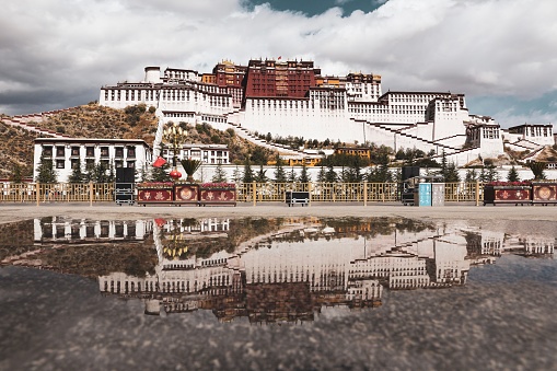 An aerial view of a traditional palace building with a cloudy sky in the background: Potala Palace, Lhasa, China.