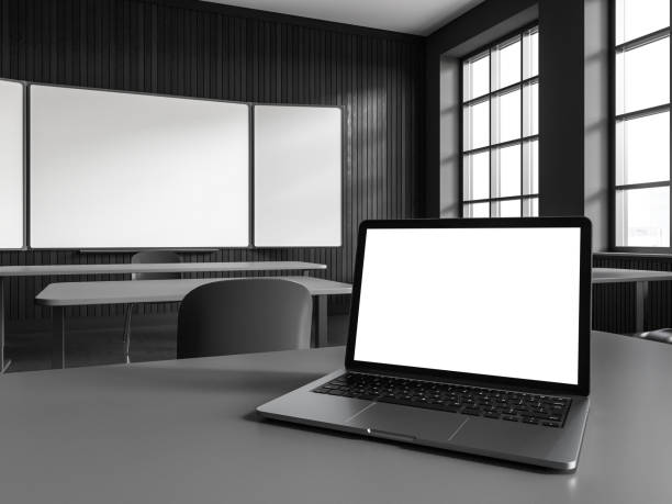 istock Dark wooden classroom interior with table in row and mockup laptop display 1551390643