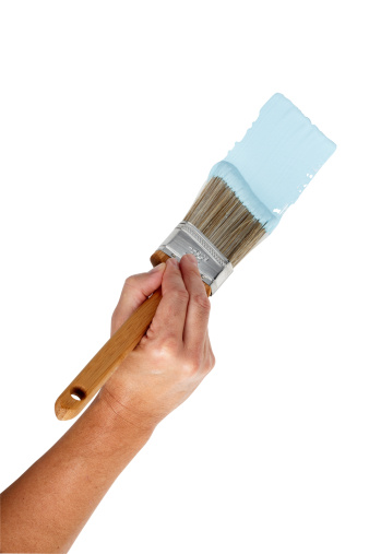 Hand with angle brush painting blue paint on blank wall, larger files come with clipping path.
