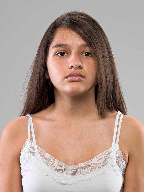 Serious thirteen years old hispanic girl Serious thirteen years old hispanic girl on gray background sad 15 years old girl stock pictures, royalty-free photos & images
