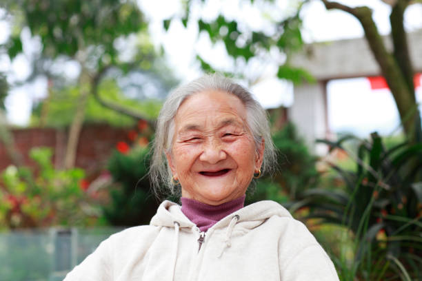 ritratto di donna anziana asiatica guardando fotocamera sorriso - toothless smile foto e immagini stock