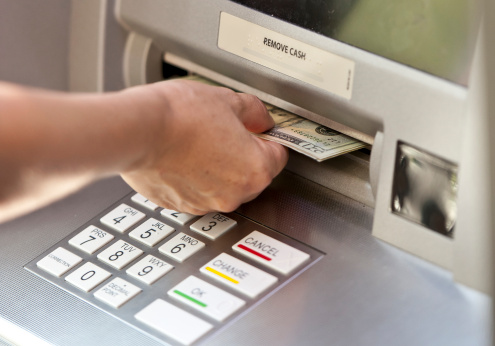 Man using a street ATM machine and withdrawing money, close up photo