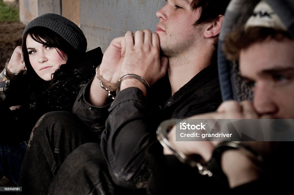 Young Caucasian Man In Handcuffs Under Arrest Two Young men and one woman handcuffed and under arrest Arrest Stock Photo