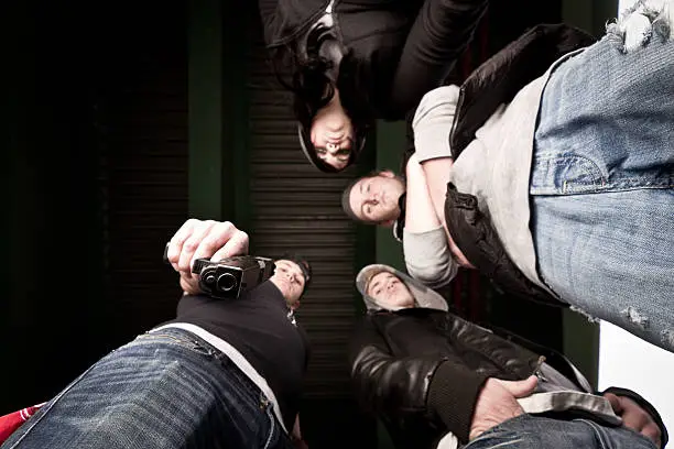 Upward View of Gang Pointing Pistol at camera on the ground