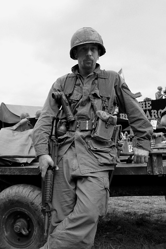 US Air Cavalry soldier  from the Vietnam war era stands next to a military vehicle.Picture has been aged to give the feel of a vintage photograph.
