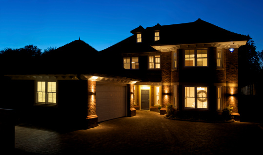 a view of a new house taken after sunset with all of the internal and exterior lights switched on. This is a large prestige house built to the highest of standards.