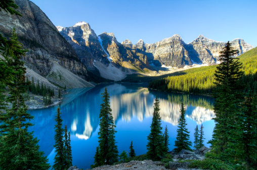 Beautiful Moraine Lake in Alberta, Canada with the mountains reflected in the blue glacial waters.