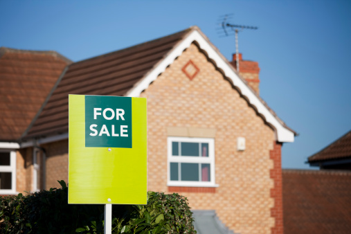 English suburban house with a 'For Sale' sign outside, in the suburbs of a city, United Kingdom.