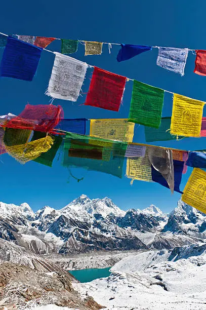 Colourful Budhist prayer flags flying in the deep blue high altitude skies above the iconic summit pyramid of Mt. Everest (8848m) and the dramatic snow capped Himalayan mountain peaks of the Khumbu, Nepal. ProPhoto RGB profile for maximum color fidelity and gamut.