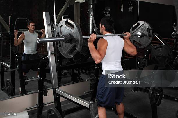 Masculino Jovem Muscular Levantando Pesos Em Frente Do Espelho - Fotografias de stock e mais imagens de Agachar-se