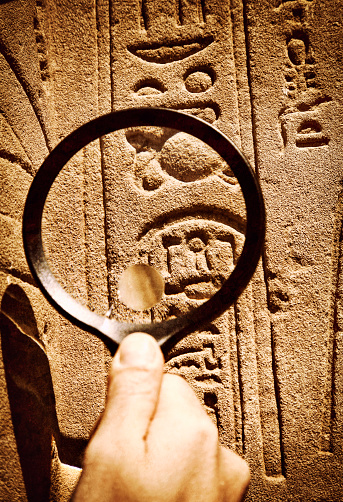 Archeologist reading hieroglyphics with magnifying glass