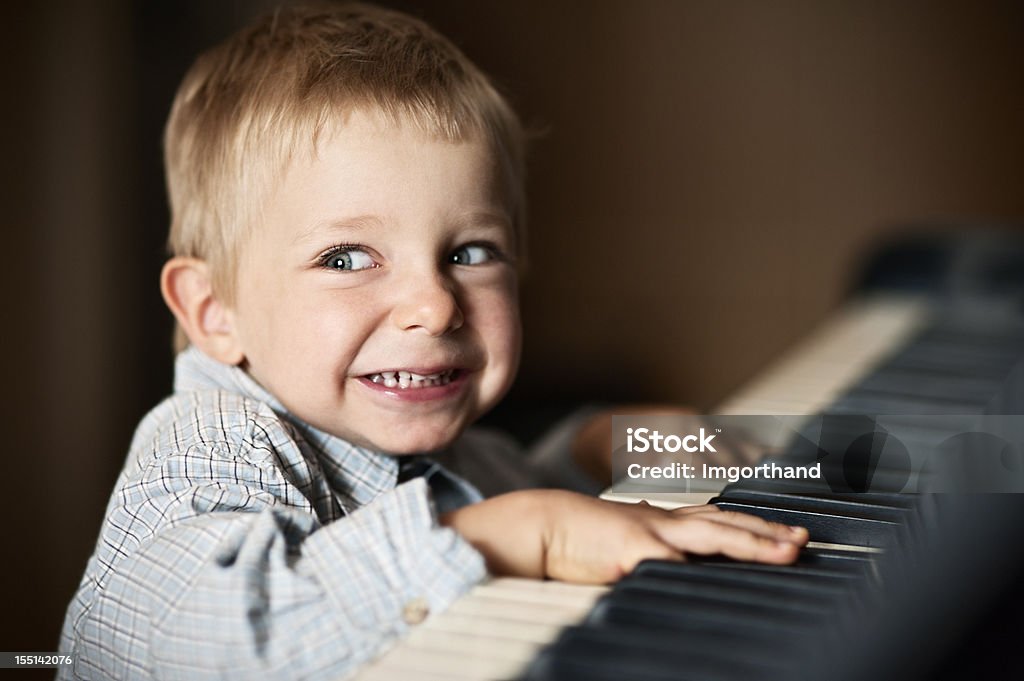 Missed a note Little boy learning to play piano. Glancing at the teacher after having missed a note. Slightly soft focus, noise applied. Fun Stock Photo