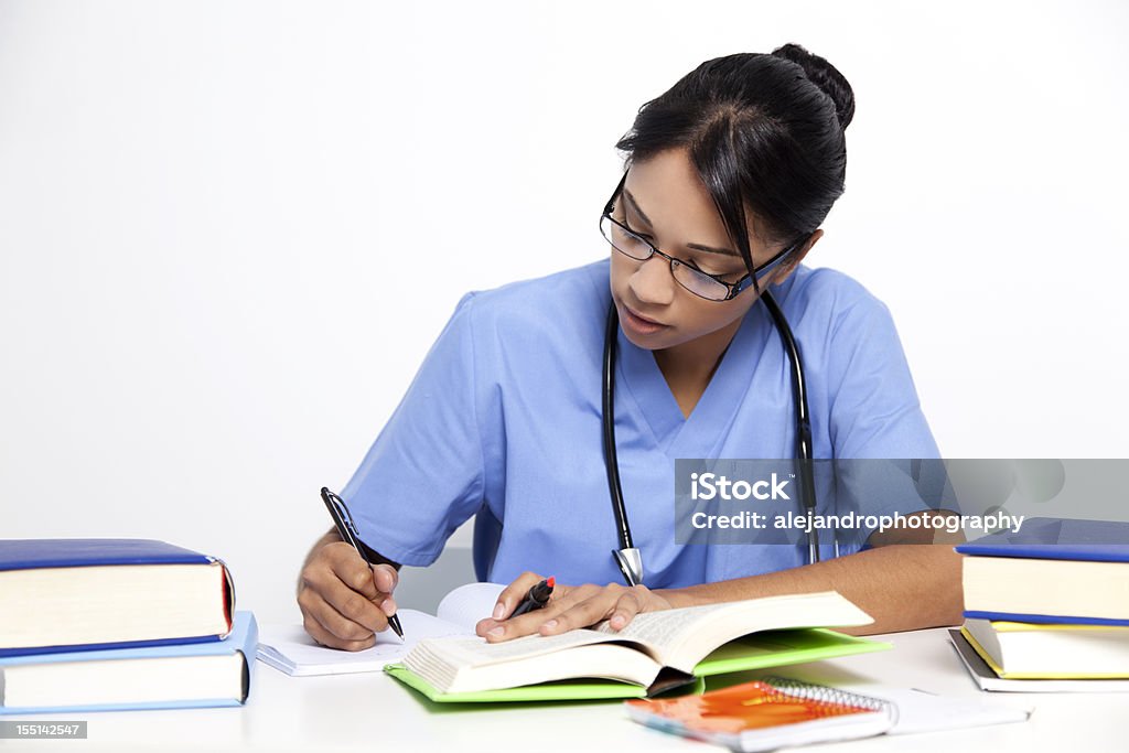 Medical nurse studying for her exams Beautiful mixed race woman with black hair wearing a blue medical scrub uniform along with a stethoscope while studying. Nurse Stock Photo