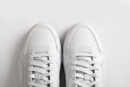 Pair of white sneakers on a white background, top view. Light shoes close-up