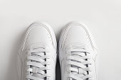 Pair of white sneakers on a white background, top view.