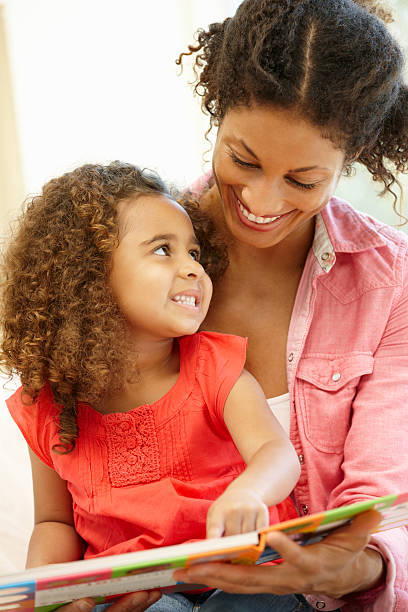 istock Smiling mixed race woman and young daughter reading a book 155142746
