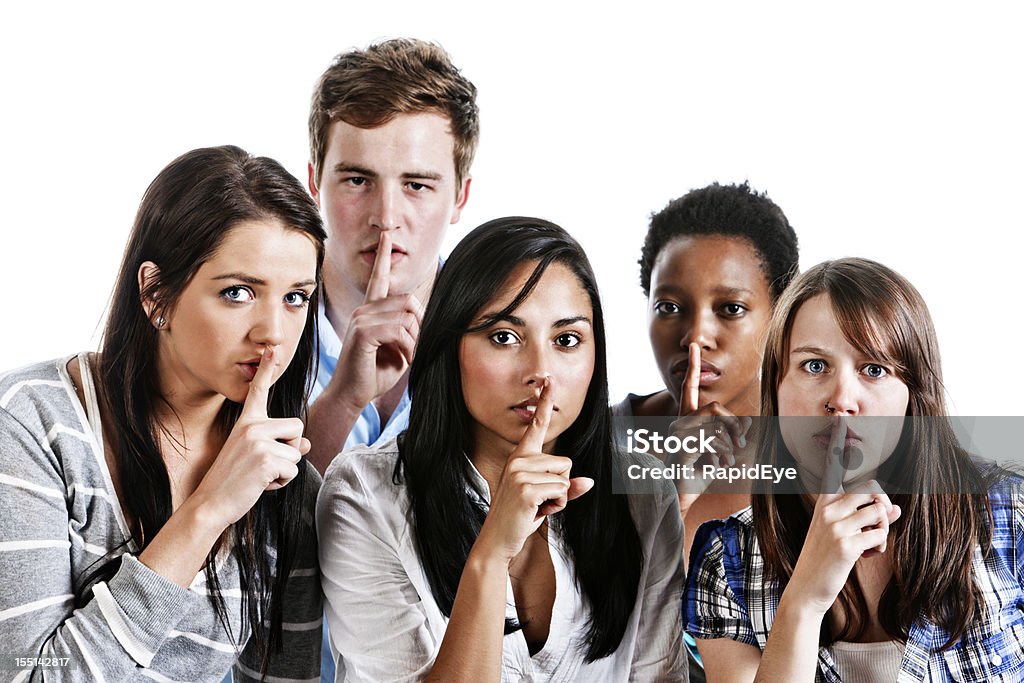 Shhh. Cinco jóvenes con los dedos para los labios - Foto de stock de Dedo sobre labios libre de derechos