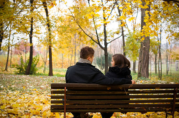 istock Young couple sitting on bench in park 155142855