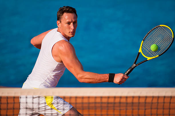Tennis player on the blue background Front view of male tennis player at backhand volley backhand stroke stock pictures, royalty-free photos & images