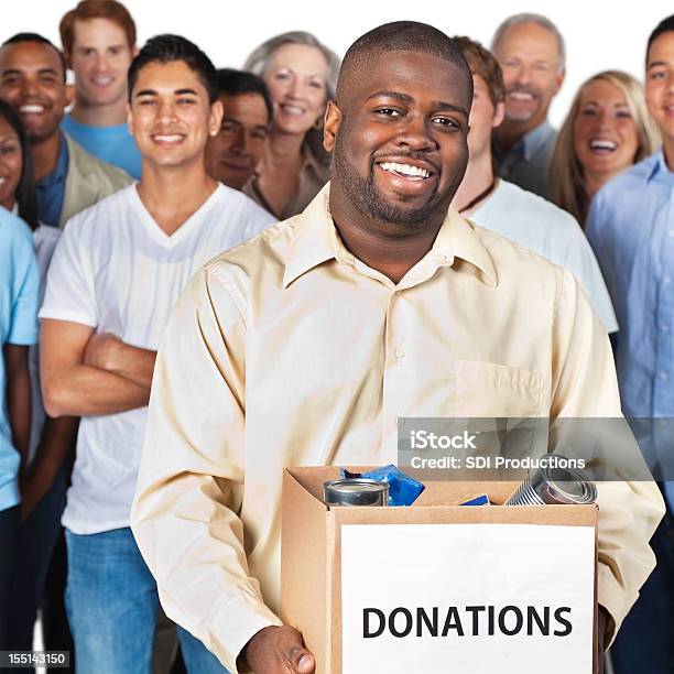 Homem Segurando A Caixa De Doação Na Frente Do Grupo - Fotografias de stock e mais imagens de Ajuda Humanitária