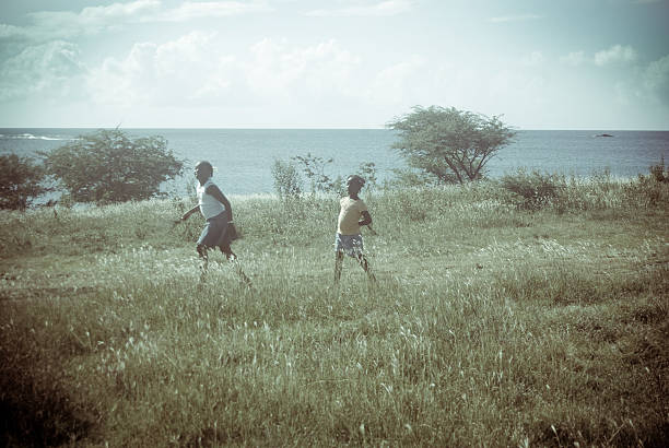 retro look; girls running in grassy field with sea landscape old film look of two girls running in grassy field with sea landscape grass area photos stock pictures, royalty-free photos & images