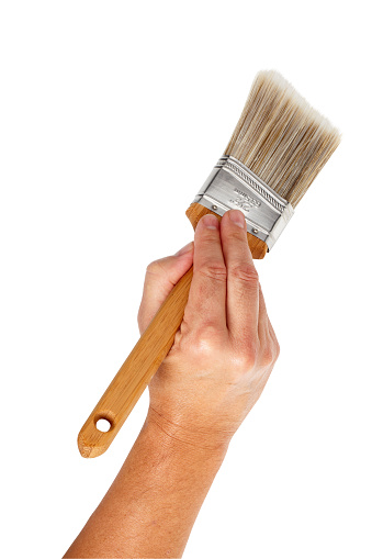 Hand holding paintbrush isolated on white background, larger files include clipping path.