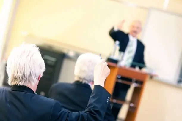 Photo of Senior student raising hand at a business seminar