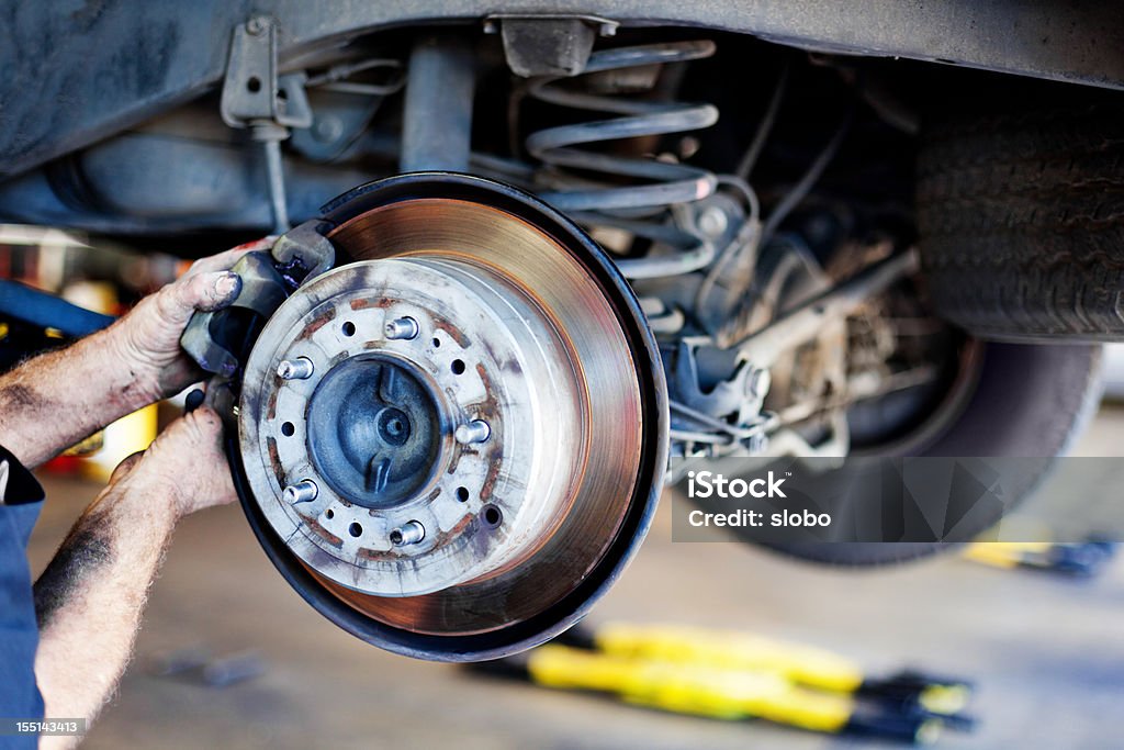 Car Brakes Repair Auto mechanic working on brakes in a car repair shop. Shallow DOF Brake Pad Stock Photo