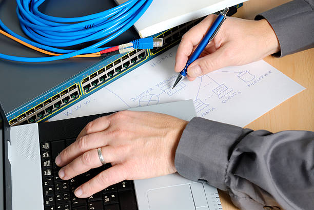 Engineer working with a laptop and paper Workplace of a computer specialist. Engineer is planning and building up a computer network. computer plan fiber optic engineer stock pictures, royalty-free photos & images