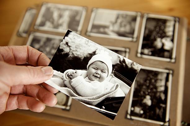 Childhood Mature person's hand holding sepia toned 1950s style photograph of young baby in pram 1950 1959 photos stock pictures, royalty-free photos & images
