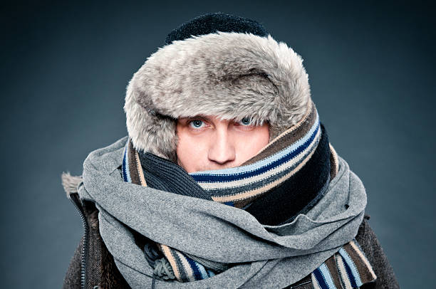 Man in winter clothes is tightly bundled up, cap, scarves stock photo