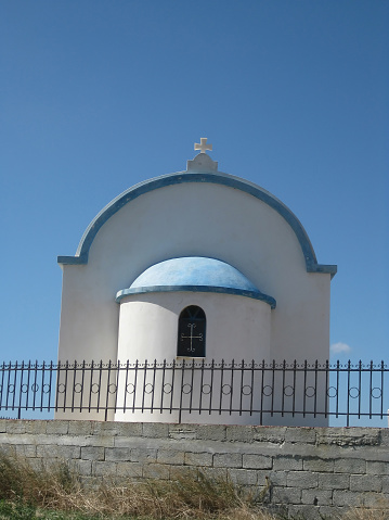 A typical old church/chapel with a small dome in the picturesque old town of Imerovigli village. In the background the famous Santorini caldera, which is for a big part under the sea leval. Location: Santorini island, Greece.