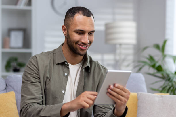istock Close-up photo. Young hispanic man using tablet at home. dials, chats, talks via video call 1551446130