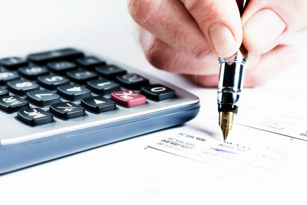 istock Man's hand checks financial document using fountain pen and calculator 155144832
