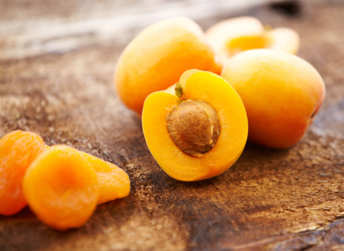 Organic fresh and dried apricots on distressed wooden surface, close-up