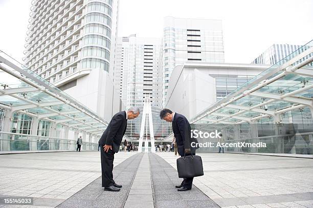 Two Businessman Bowing To Each Other On A Pedestrian Bridge Stock Photo - Download Image Now
