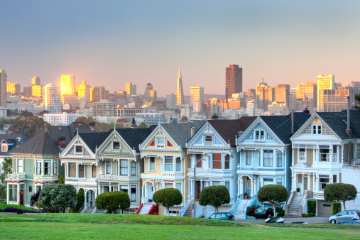 Shot of the painted ladies / postcard row, with San Francisco skyline as the backdrop during sunset.