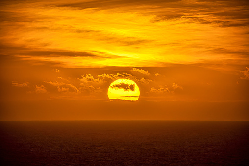 Big sun at sunset in the sea on the horizon