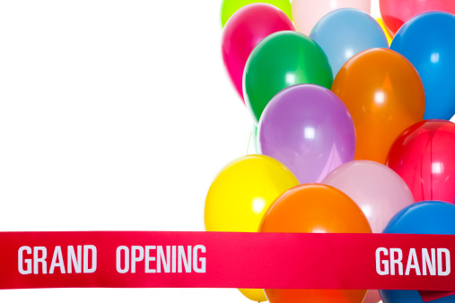 Several colorful helium balloons and Grand Opening ribbon. Copy space to add company info or additional text.