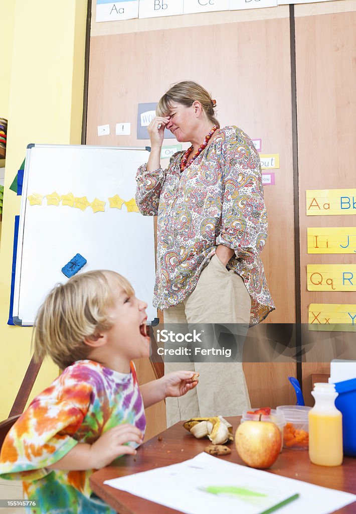 Stressed teacher in the classroom A photograph of a stressed out teacher with a headache in a noisy classroom. Teacher Stock Photo