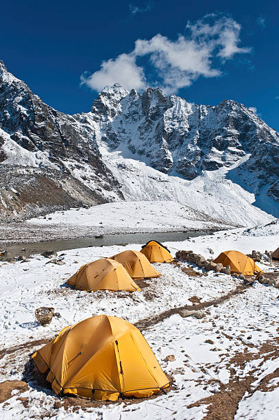 Bright yellow expedition dome tents snow mountain camp Himalayas Nepal Vibrant yellow dome tents pitched in a snowy camp high in the dramatic Himalayan mountain scenery of the Everest National Park, Nepal, under deep blue skies. ProPhoto RGB profile for maximum color fidelity and gamut. base camp stock pictures, royalty-free photos & images