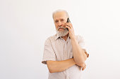 Studio portrait of serious elderly adult male with beautifully elegant beard and mustache having mobile conversation using smartphone with friends