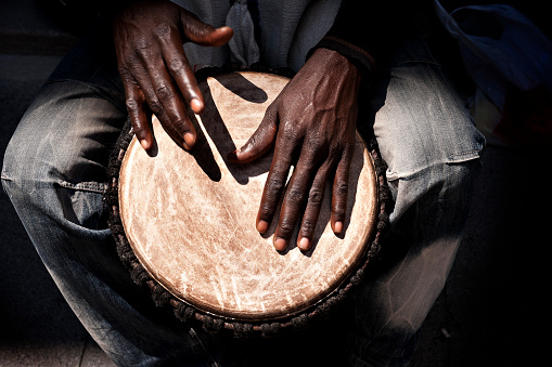 Close up of hands of a black man playing a jembe