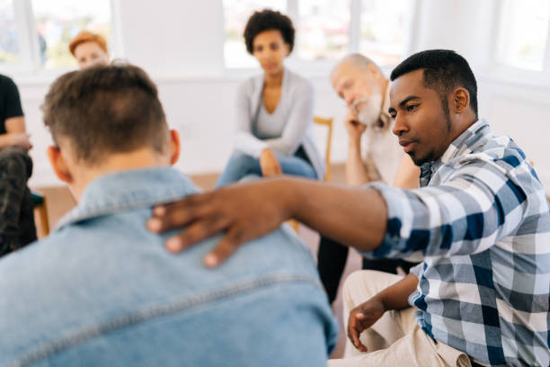 Closeup back view of unrecognizable sad man sharing life problem grief with multiracial people in modern mental health support group session in rehab center.