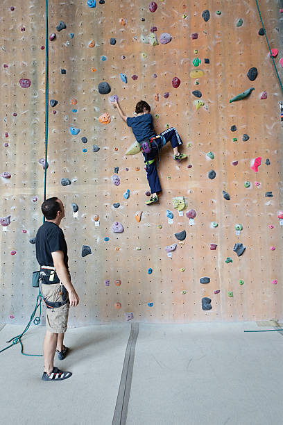 Boy on a rock climbing wall stock photo